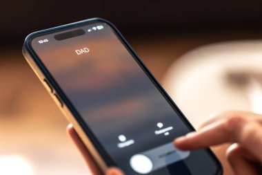 Bulanık bir arkaplanda baba çağrısının görüntülendiği telefonu tutan çocuk ellerini kapat.