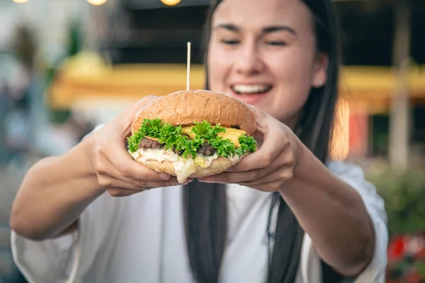 Μια Ελκυστική Νεαρή Γυναίκα Στα Χέρια Κατέχει Ένα Burger Τρώει — Φωτογραφία Αρχείου