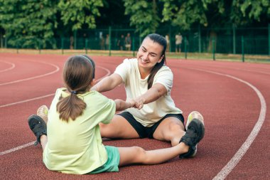 Anne ve kız spor için dışarı çıkıyorlar, beyaz kadın ve küçük kız stadyumda spor yapıyorlar..