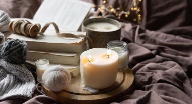 Mumlarla, kitaplarla ve yatakta örülmüş elementlerle sıcak ev kompozisyonu, kışlık ev kavramı.