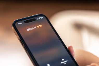 Akıllı telefon çocuğun elinde. Gelen anne ekranda bulanık bir arkaplanı kapatıyor..