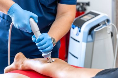 Şok dalgası terapisi, manyetik alan, rehabilitasyon, fizyoterapist doktor bir hastanın bacağını ameliyat eder..