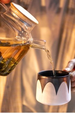 Bir kadın gece geç saatlerde fincana çay doldurur. Çay içme, sinirleri yatıştırma, uyumak için bitki çayı..