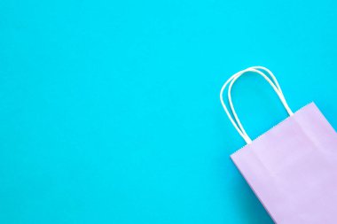 Mavi arkaplanda leylak kağıt çanta, üst görünüm, online alışveriş konsepti, kopyalama alanı.