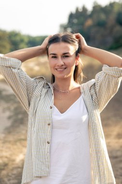 Uzun saçlı, beyaz elbiseli ve gömlekli mutlu bir esmer kadının yaz portresi..