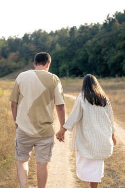 Bir adam ve bir kadın, el ele tutuşmuş, mutlu bir aile, birbirine aşık bir çift, arkadan bakıyorlar..