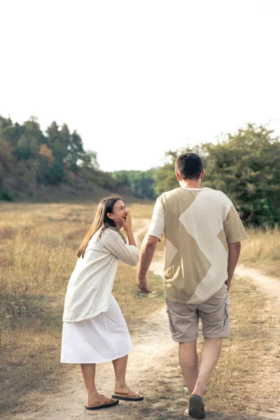 Happy man and woman walking in the field, the concept of close relationships in a couple, strong marriage, time together.