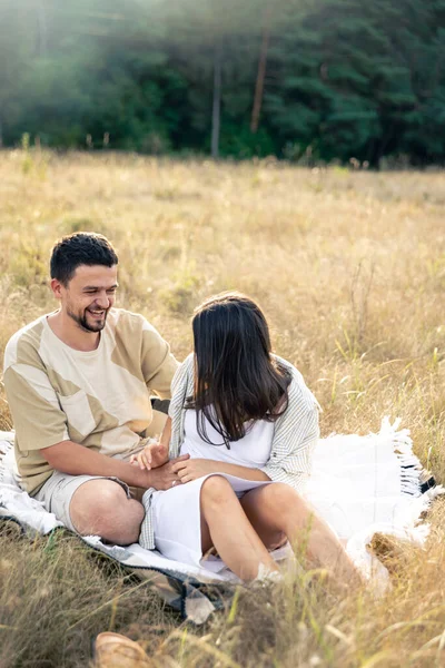 Happy married man and woman on a date relaxing in the field in summer, laughing together, close relationship, romance in marriage.