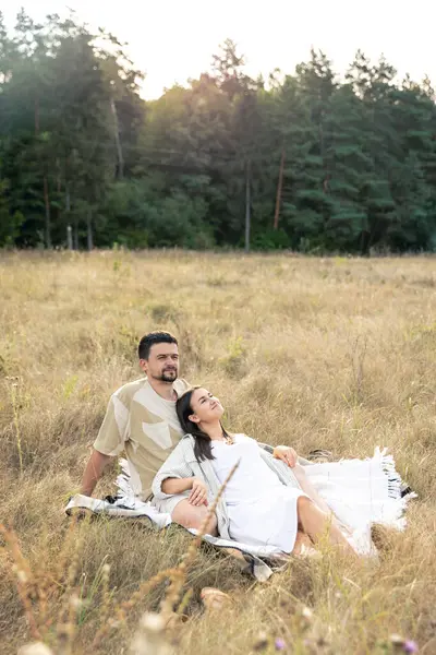Happy married man and woman on a date relaxing in a field in summer, quality time together, close relationship, romance in marriage.