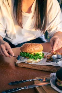 Kadın eli fast food burgeri, Amerikan sağlıksız kalori yemeği, ızgara hamburgerli aç bir insan..