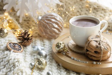 Kış kompozisyonu. Bir fincan kakao ve çikolatalı kurabiye. Arka planda bulanık ve Noel dekorlu..