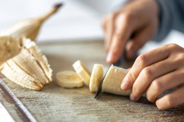 Kadının biri kesim tahtasıyla muz kesiyor, yakın plan..