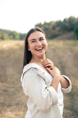 Uzun saçlı, beyaz elbiseli ve gömlekli mutlu bir esmer kadının yaz portresi..