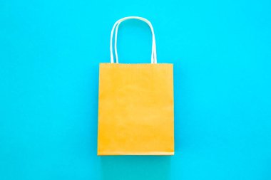 Mavi arkaplanda turuncu kağıt çanta, üst görünüm, çevrimiçi alışveriş kavramı, kopyalama alanı.