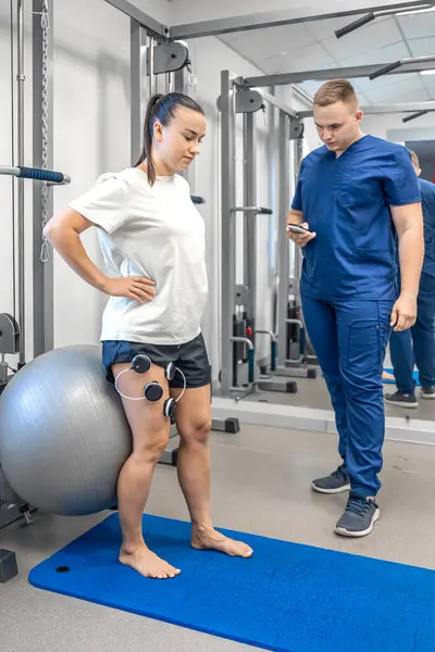 The procedure of myostimulation on the legs of a woman, rehab physiotherapy in gym.