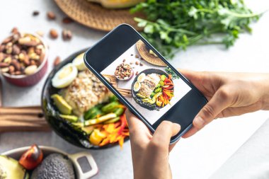 Bir kadın akıllı telefonuyla sebze kasesinin fotoğrafını çekiyor, bir blogcu Asya yemeklerinin fotoğraflarını çekiyor..