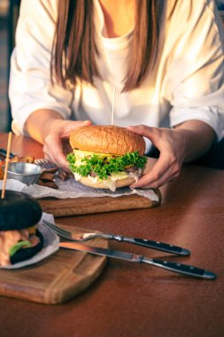 Kadın eli fast food burgeri, Amerikan sağlıksız kalori yemeği, ızgara hamburgerli aç bir insan..