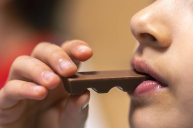 Bir kızın detaylı görüntüsü çikolatayı ısırıyor, yakından..