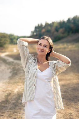 Uzun saçlı, beyaz elbiseli ve gömlekli mutlu bir esmer kadının yaz portresi..