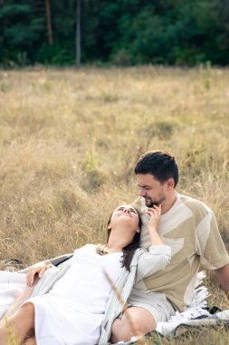 Mutlu evli erkek ve kadın, yazın bir tarlada rahatlıyor, birlikte kaliteli zaman geçiriyor, yakın ilişki, evlilikte romantizm..