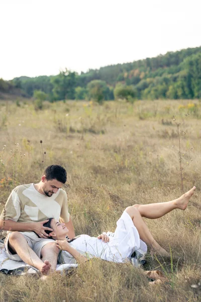 Happy married man and woman on a date relaxing in a field in summer, quality time together, close relationship, copy space.