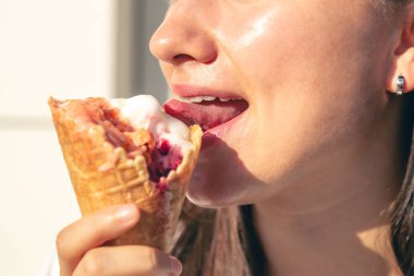 Genç bir kadın, sıcak bir yaz gününde gözleme külahında lezzetli dondurmalar yer..