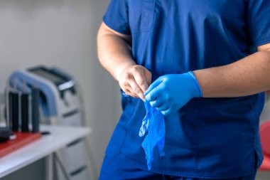 Tıbbi klinikte erkek doktorların ellerini mavi sterilize cerrahi eldiven giyerken yakın çekim görüntüsü..