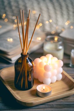 Tütsü çubukları, mumlar, kitaplar ve ahşap bir yüzey üzerindeki bokeh ışıklarıyla kış sıcacık spa kompozisyonu.