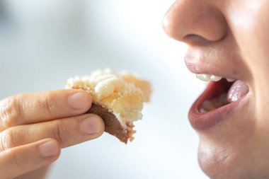 Bir kadın rendelenmiş peynirli ekmek yer, yakın plan, kahvaltı konsepti..