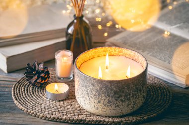 Sıcak kış kompozisyonu. Arka planda mumlar, kitaplar ve bokeh ışıkları var..