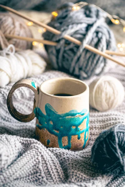 Cozy winter composition with a handmade cup of coffee, threads and knitted element, handmade concept.