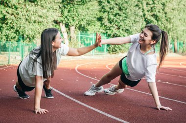 Stadyumda esneme egzersizleri yapan genç kadınlar antrenmandan önce kaslarını ısıtıyorlar...