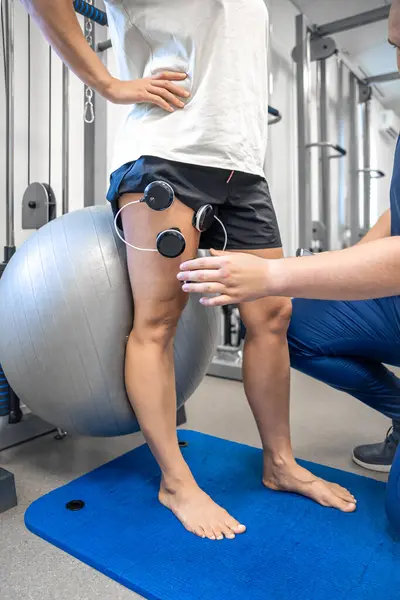 The procedure of myostimulation on the legs of a woman, rehab physiotherapy in gym.