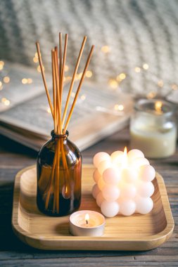 Tütsü çubukları, mumlar, kitaplar ve ahşap bir yüzey üzerindeki bokeh ışıklarıyla kış sıcacık spa kompozisyonu.