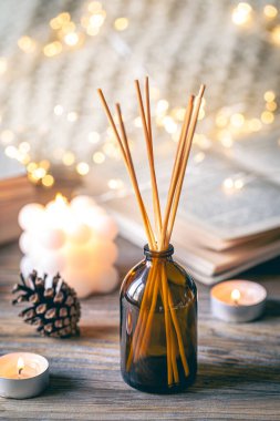 Tütsü çubukları, mumlar, kitaplar ve ahşap bir yüzey üzerindeki bokeh ışıklarıyla kış sıcacık spa kompozisyonu.