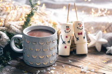 Bulanık arkaplanda bir fincan kakao ve marshmallow kardan adam ile kış kompozisyonu.