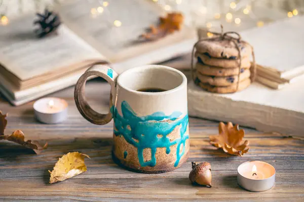 Cozy autumn composition with a handmade cup, autumn leaves and books.
