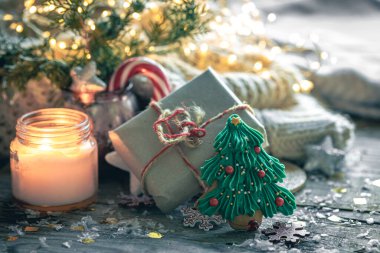 Yanan bir mum ve dekoratif detaylarla samimi Noel kompozisyonu, kış havası, tatil süsü, sihirli Noel.