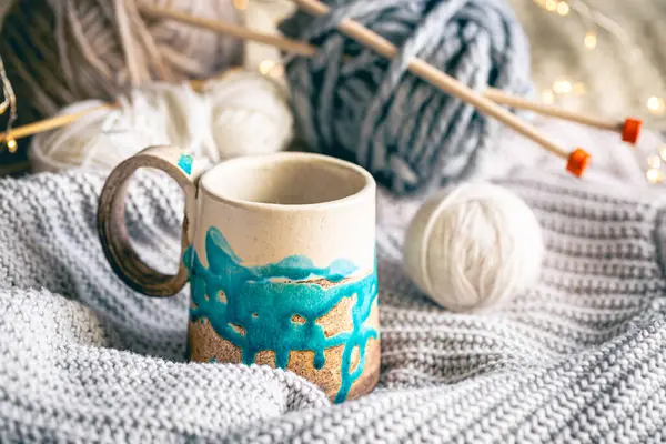 Cozy winter composition with a handmade cup of coffee, threads and knitted element, handmade concept.
