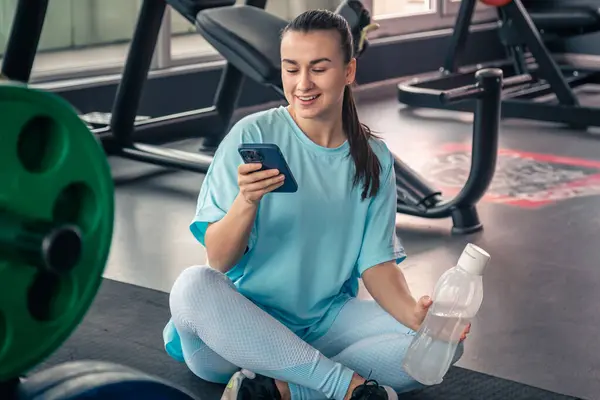 Happy woman, fitness and phone at gym for a workout, training and body wellness with a mobile app.