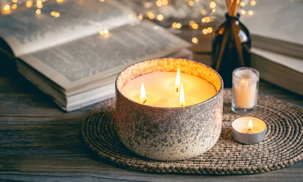 Cozy winter composition with candles, books and bokeh lights on a blurred background.