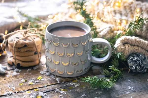 Winter composition with a cup of cocoa, cookies and decorative details on a blurred background.