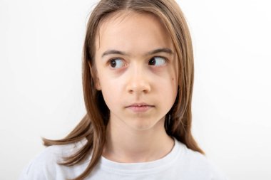 Beyaz tişörtlü komik beyaz kız beyaz bir arka planda şaşırmış bir şekilde yan tarafa bakıyor..