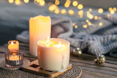 Örülmüş bir element ve çelengin bulanık arka planında yanan mumlarla dolu rahat bir hayat, boşluğu kopyala.