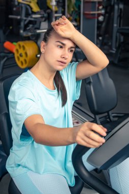 Bisikletli yorgun bir kadın spor salonunda kardiyo antrenmanı yapıyor genç bir kadın spor salonunda egzersiz yapıyor..