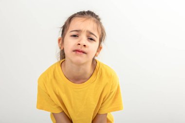 Sarı tişörtlü küçük beyaz kız, beyaz arka planda yalnız, yorgun, ilgisiz, kopya alanı olan bir çocuktan memnun görünmüyor..
