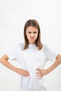 Öfkeli kız ellerini beline koyar beyaz bir arka planda, izole edilmiş, negatif duygu, asabiyet ve kırgınlık.