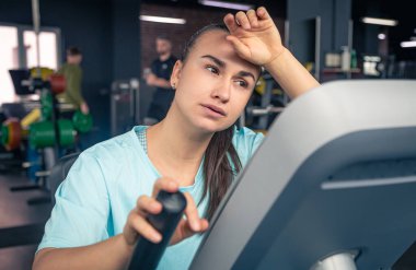Bisikletli yorgun bir kadın spor salonunda kardiyo antrenmanı yapıyor genç bir kadın spor salonunda egzersiz yapıyor..