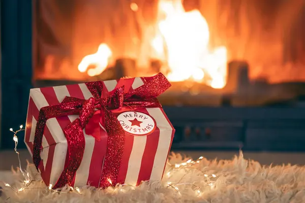 Christmas gift box by the fireplace on a background of fire, copy space.