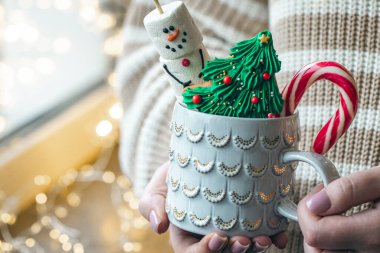 Noel ağacı şeklinde zencefilli sıcak bir bardak Noel içeceği, bir marshmallow kardan adam ve kadınların elinde şeker, boşluğu kopyala.